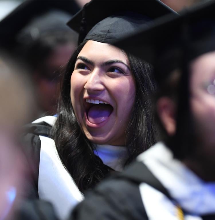 Smiling female graduate in crowd wearing regalia